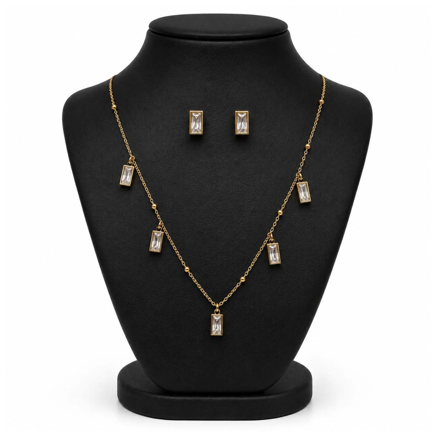 Gold-tone necklace and matching stud earrings displayed on a black jewelry bust against a white background.