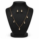 Gold-tone necklace and matching stud earrings displayed on a black jewelry bust against a white background.