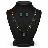 Gold jewelry set displayed on a black mannequin bust, including a necklace with green, blue, and pink baguette stones, matching rectangular stud earrings, and small round pearl-like accents.