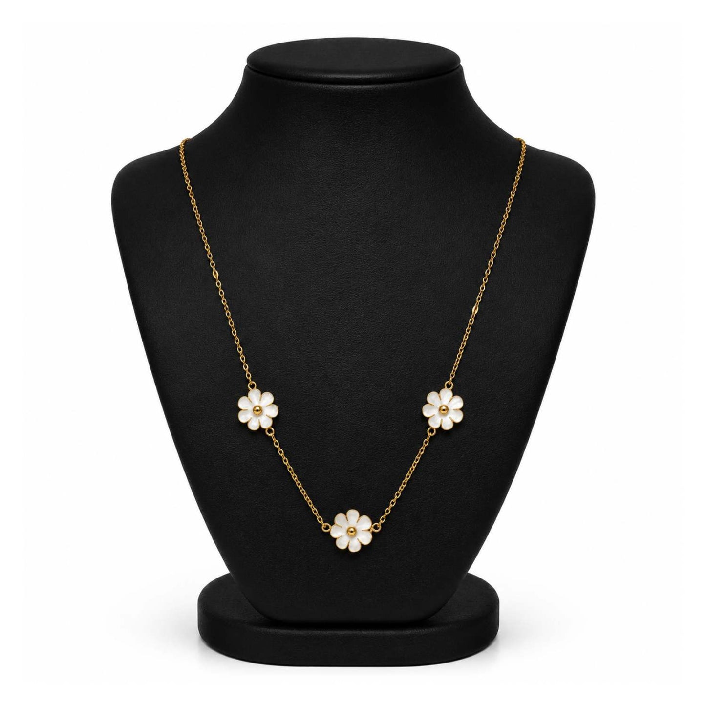 A gold chain necklace with three white flower charms, displayed on a black jewelry bust against a white background.