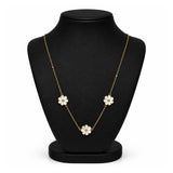 A gold chain necklace with three white flower charms, displayed on a black jewelry bust against a white background.