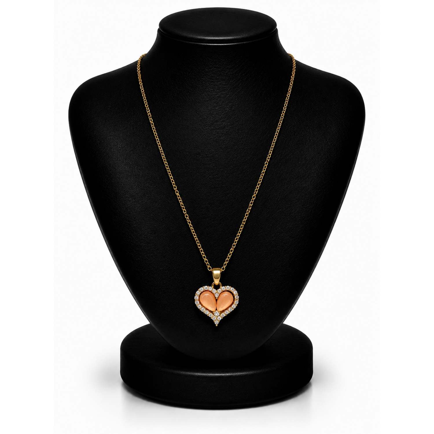 A gold heart pendant necklace with a peach-colored center, displayed on a black jewelry bust against a white background.