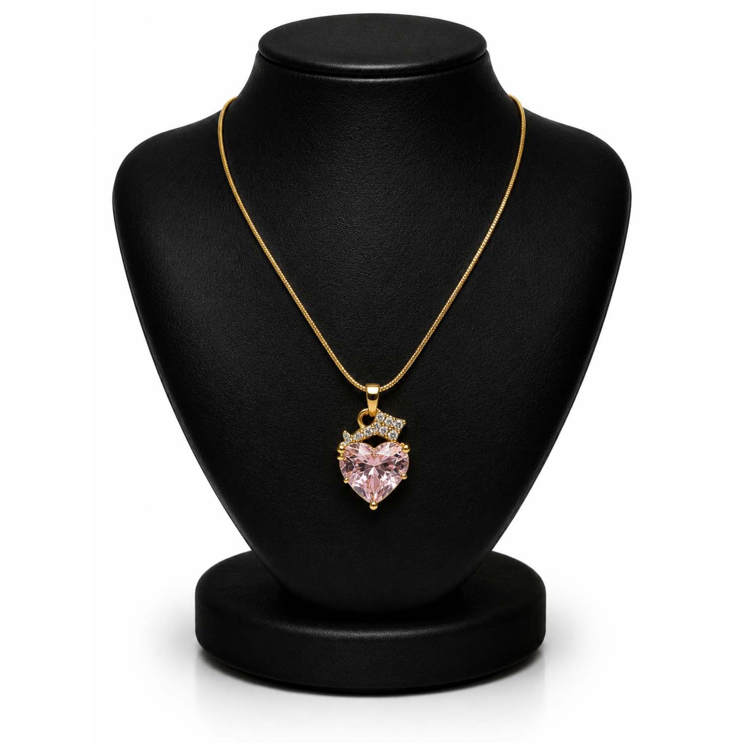 A gold chain necklace with a heart-shaped pink gemstone pendant, displayed on a black jewelry bust against a white background.