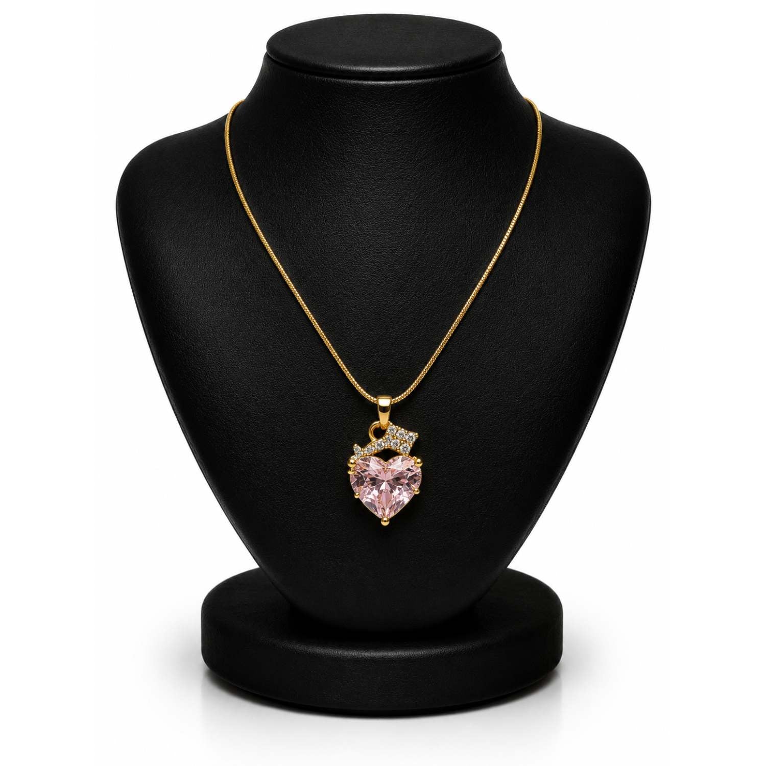 A gold chain necklace with a heart-shaped pink gemstone pendant, displayed on a black jewelry bust against a white background.
