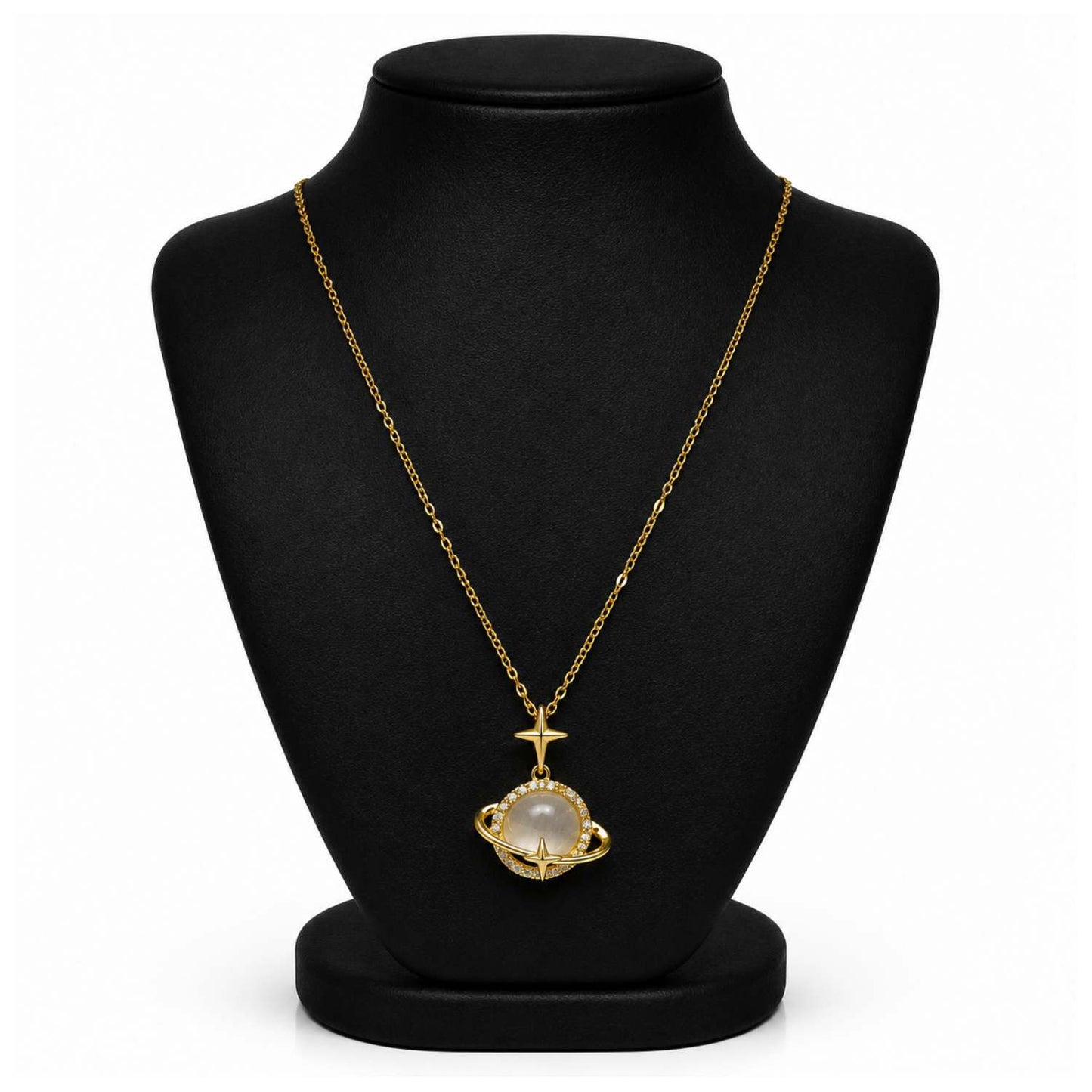 A gold chain necklace with a pendant featuring a white pearl-like stone and a small gold cross above it, displayed on a black jewelry bust against a white background.