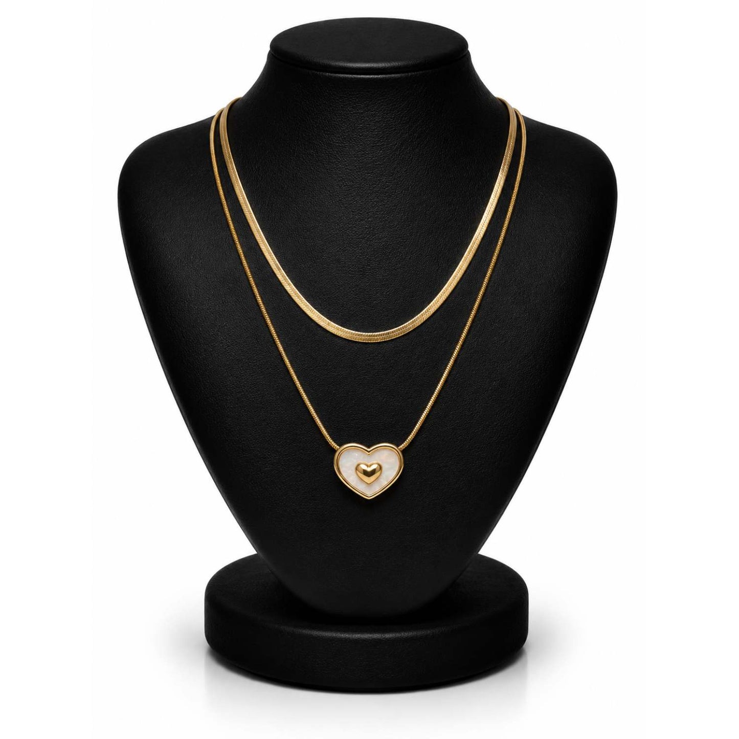 A double-strand gold chain necklace with a heart-shaped pendant displayed on a black jewelry bust against a white background.