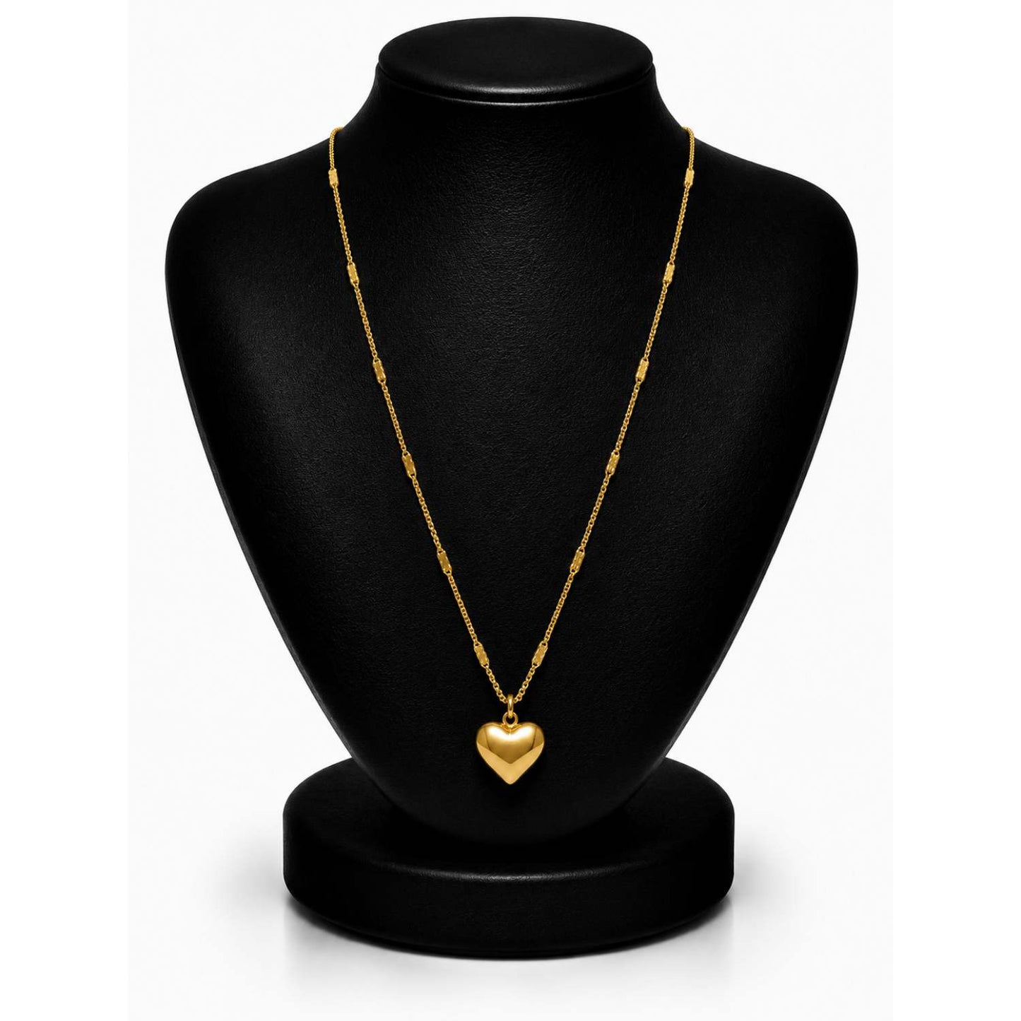 A gold heart pendant necklace displayed on a black jewelry bust against a white background.