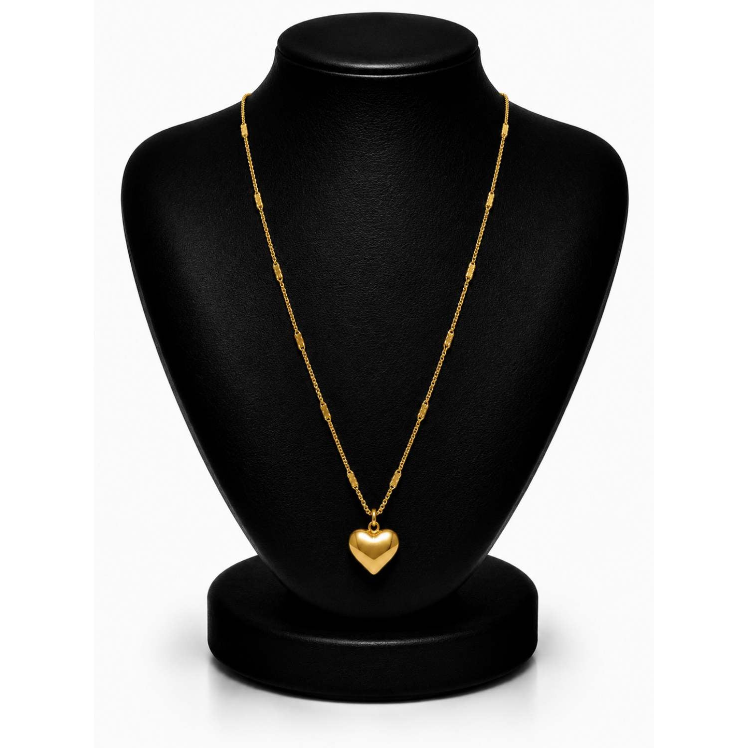 A gold heart pendant necklace displayed on a black jewelry bust against a white background.
