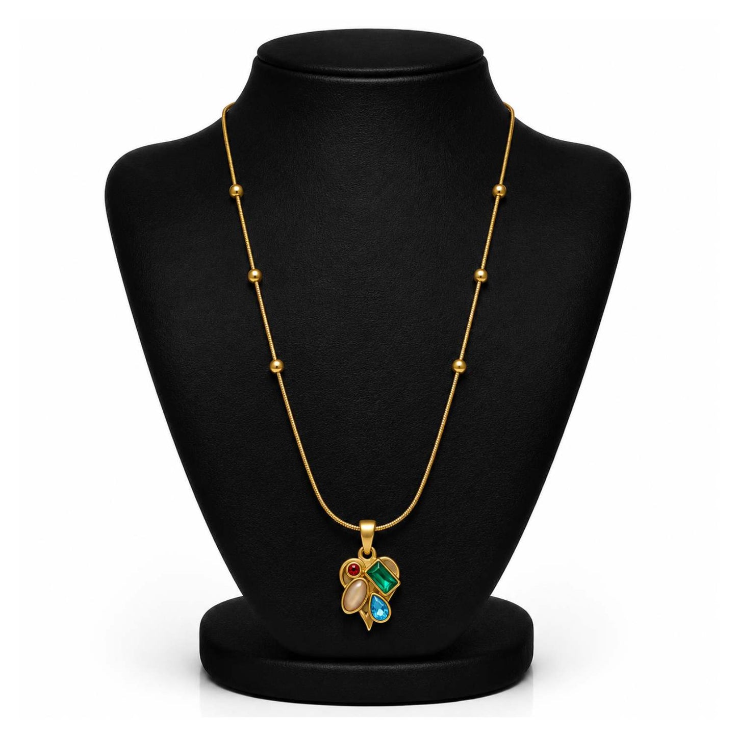 A gold necklace with a multi-colored pendant displayed on a black jewelry bust. The pendant features green, blue, and red stones set in gold.