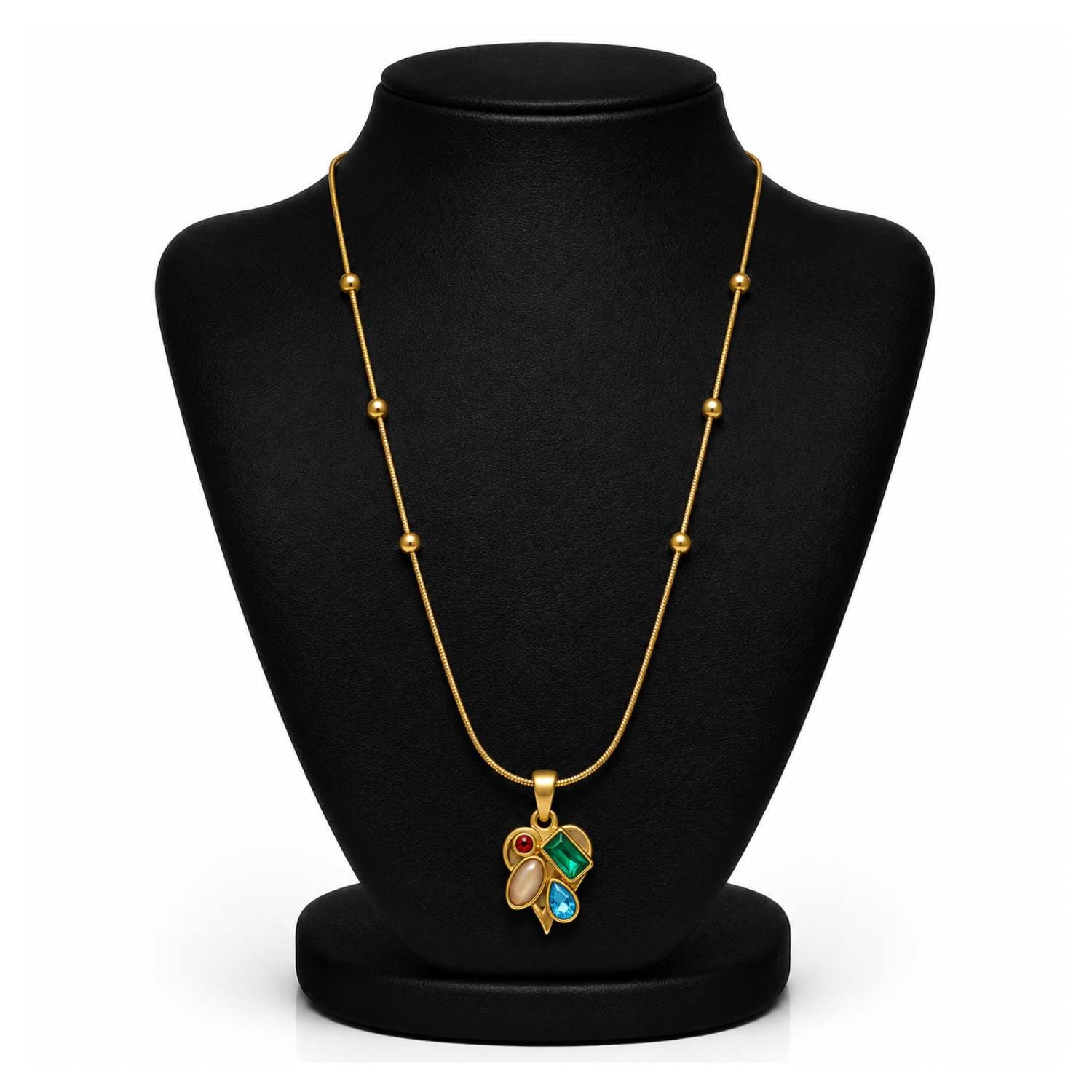 A gold necklace with a multi-colored pendant displayed on a black jewelry bust. The pendant features green, blue, and red stones set in gold.