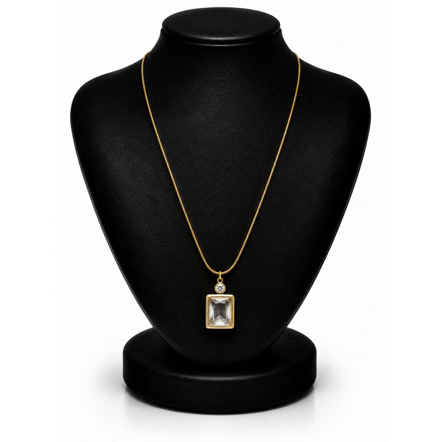 A gold chain necklace with a square bezel-set clear gemstone pendant, displayed on a black jewelry bust against a white background.